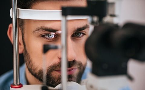Man undergoing eye exam with medical equipment focused on his eye.