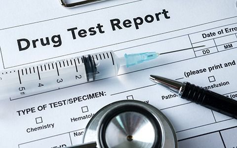 Drug test report form with a syringe, stethoscope, and pen.
