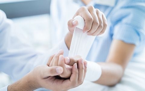 Doctor wrapping a patient's wrist with a white bandage.