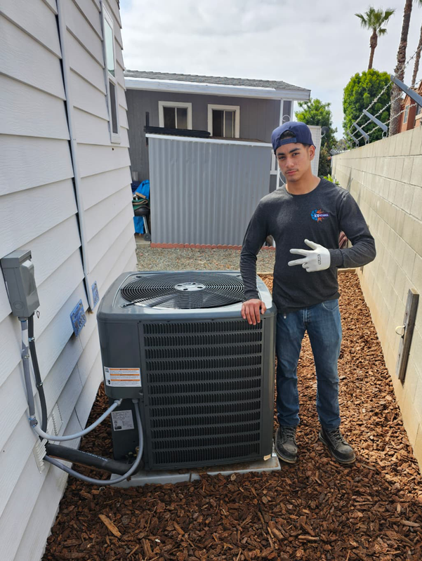 Technician standing beside an outdoor air conditioner unit in a narrow side yard