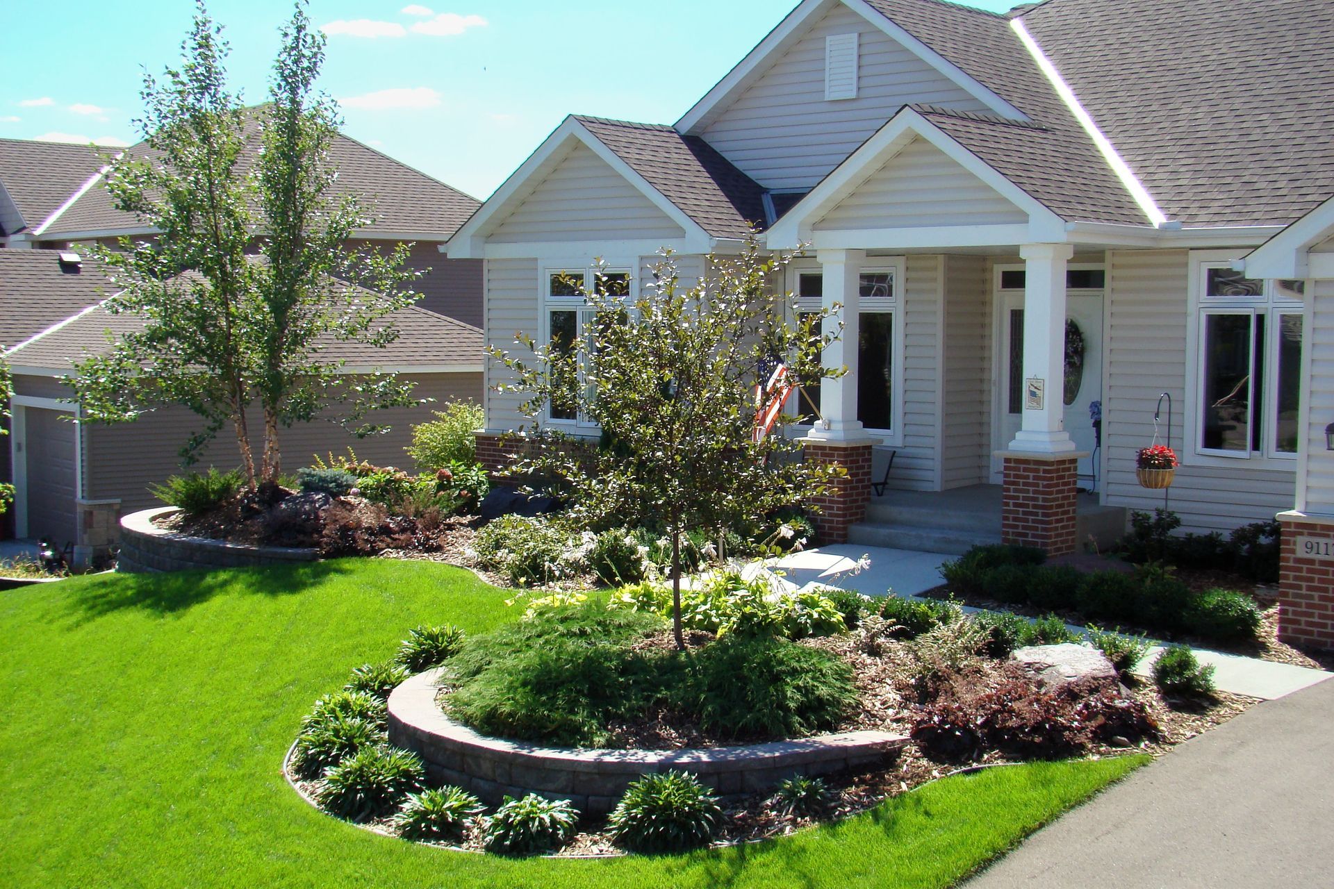 Landscaped front yard with a house featuring a garden bed bordered by a low retaining wall.
