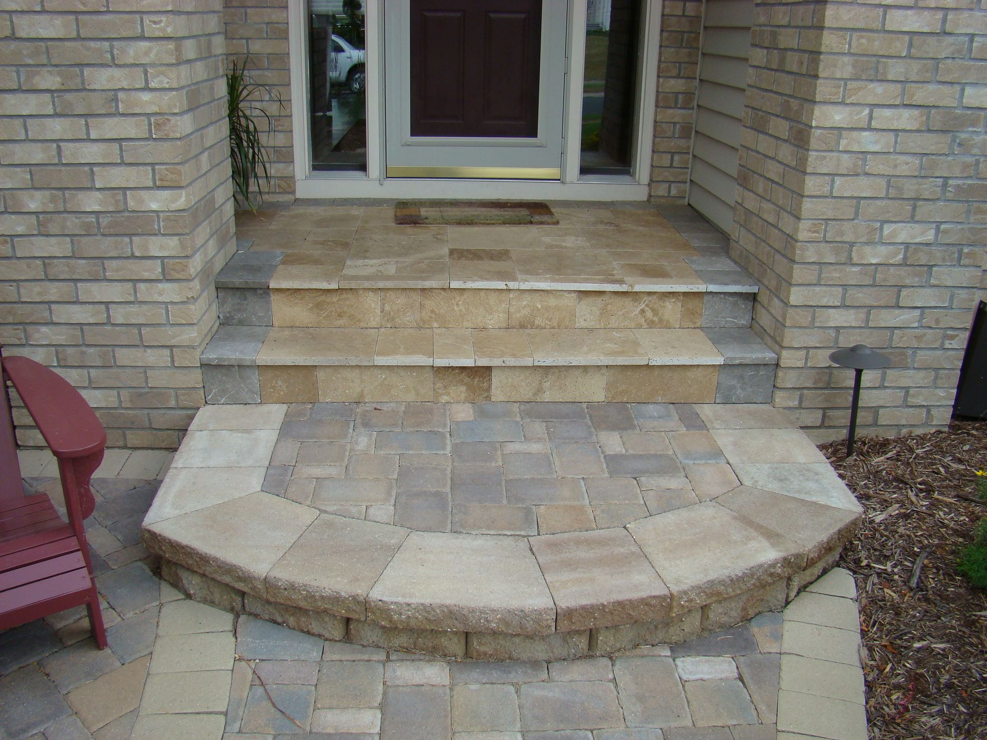 Brick home entrance with stone steps and curved landing.