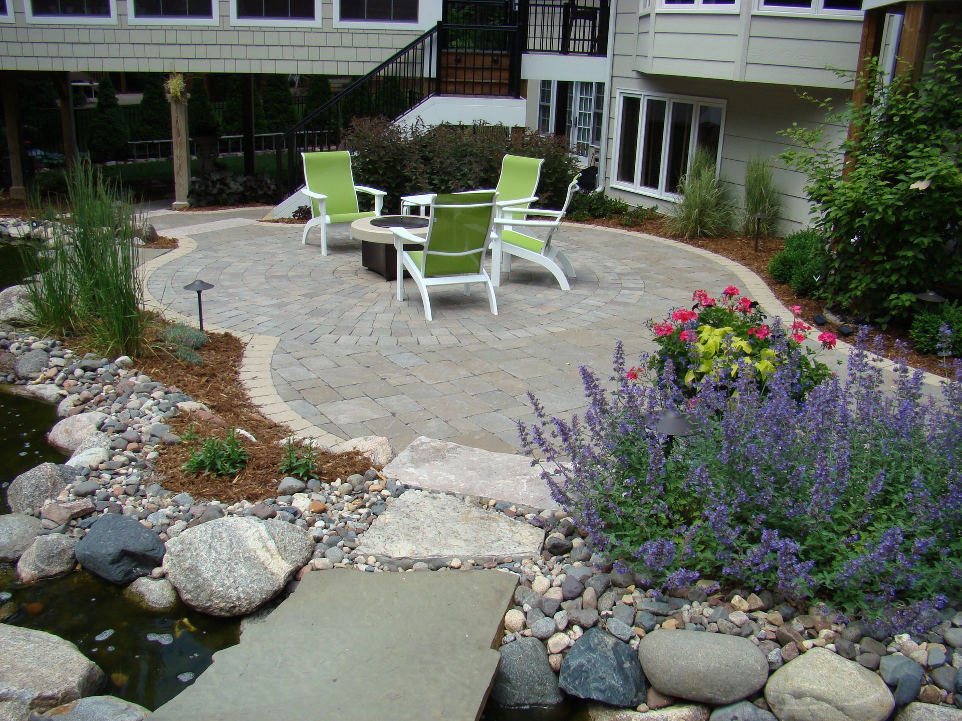 Patio with seating area, water feature, and lush landscaping in an outdoor setting.