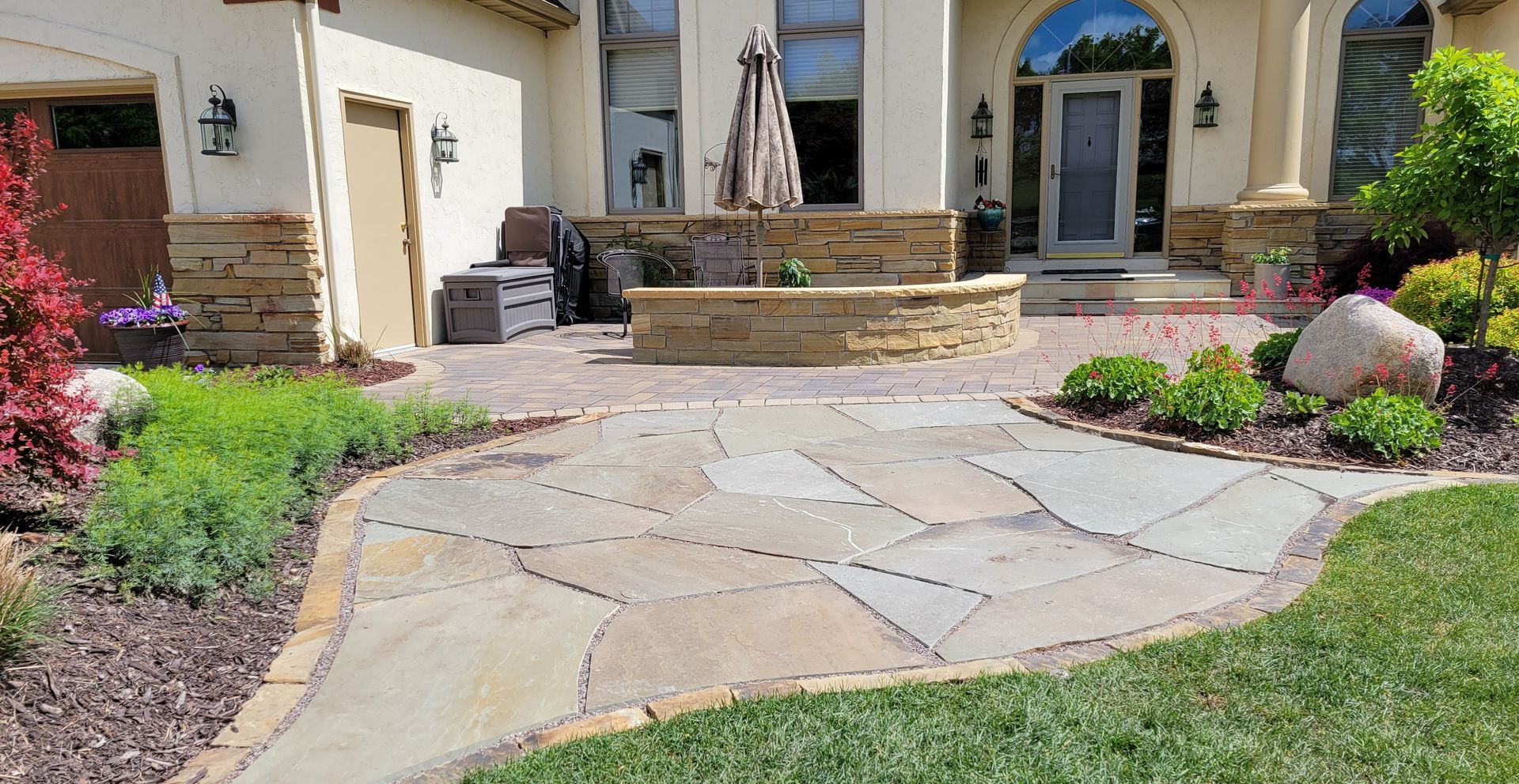 Stone walkway leading to a house with a stone patio and landscaping.