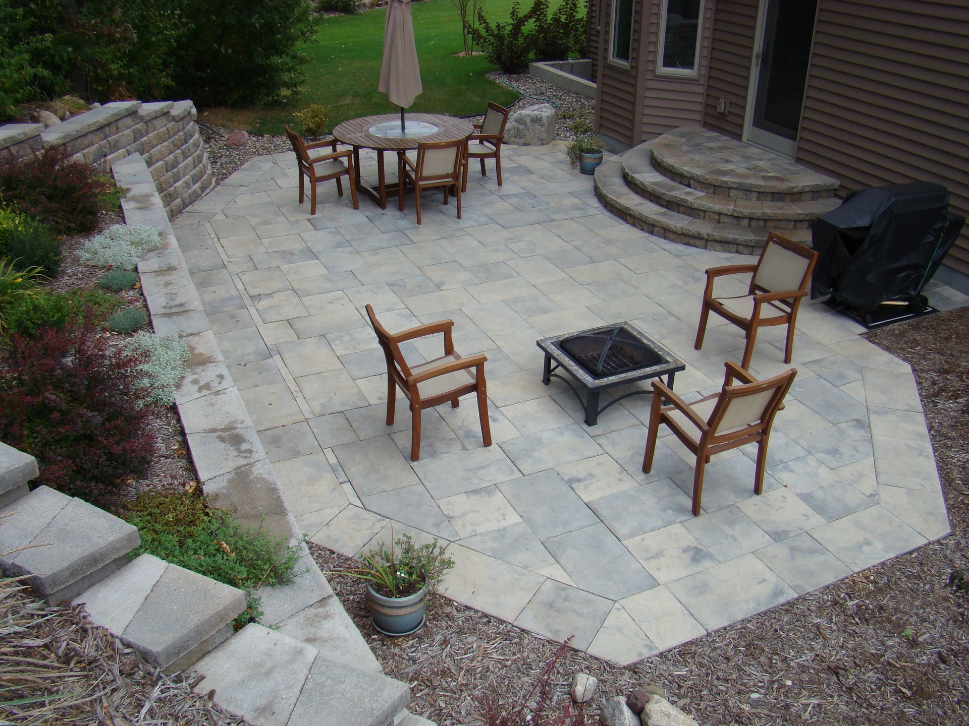 Stone patio with fire pit, seating, and a retaining wall.