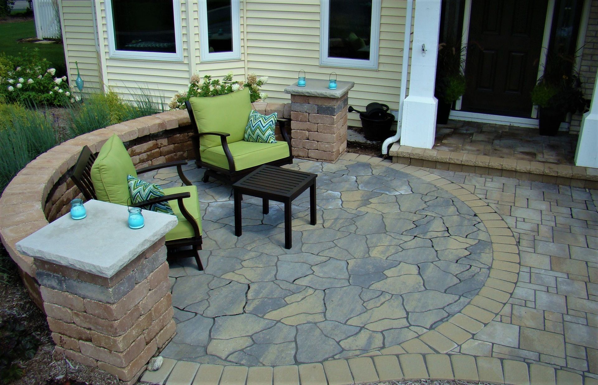 Stone patio with seating area, curved wall, and decorative pillars.