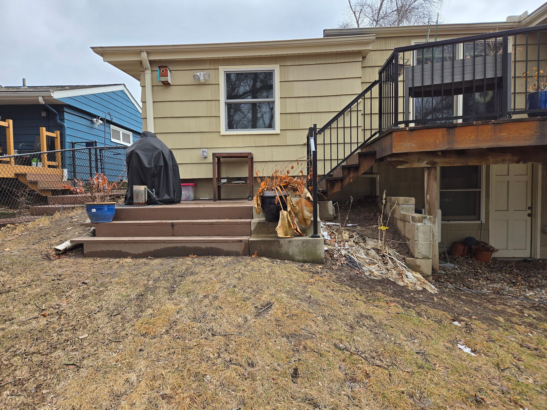Backyard view with deck, steps, grill, and house with a blue house next door.