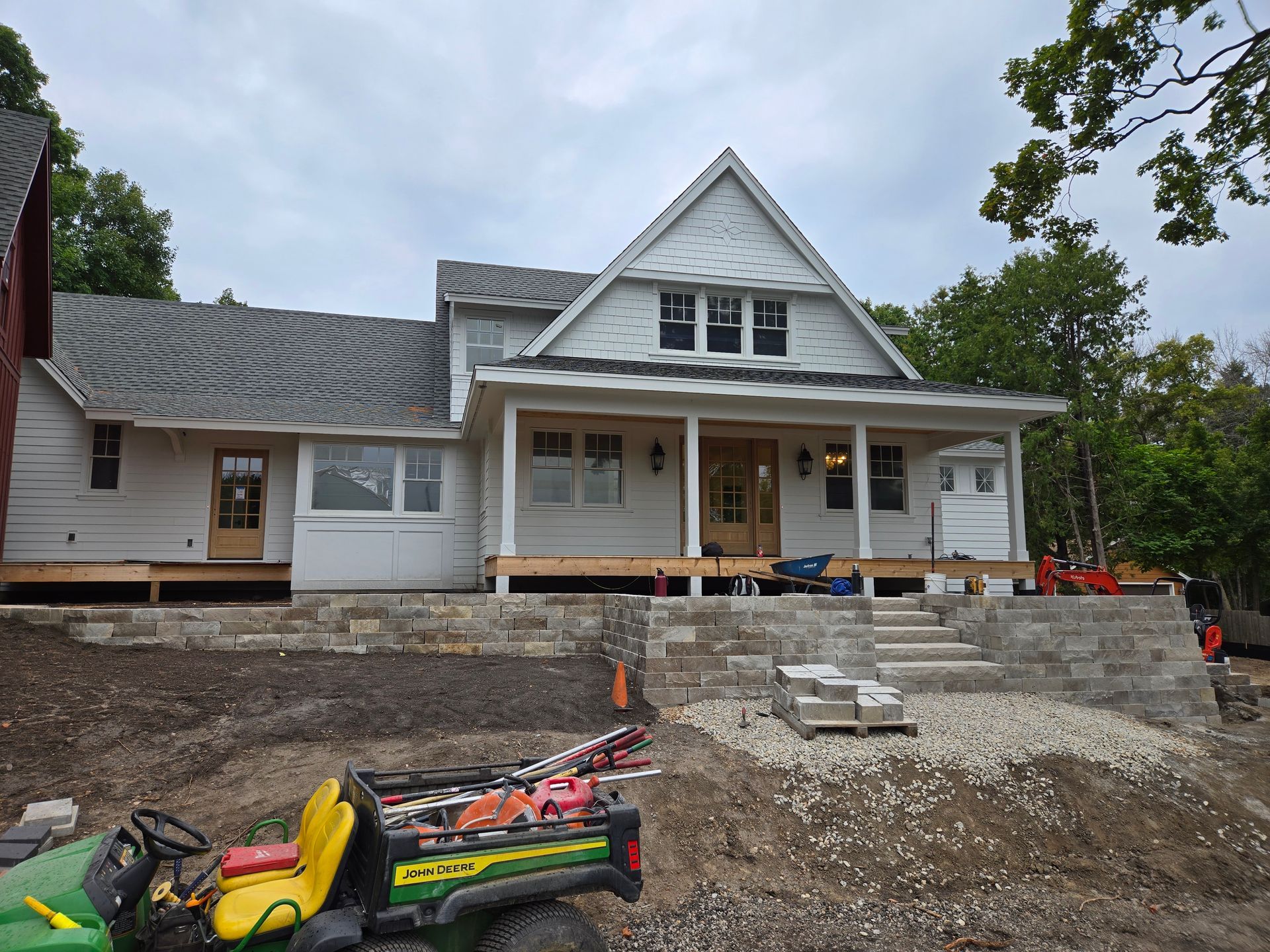 House under construction with porch and landscaping; gray and white exterior.
