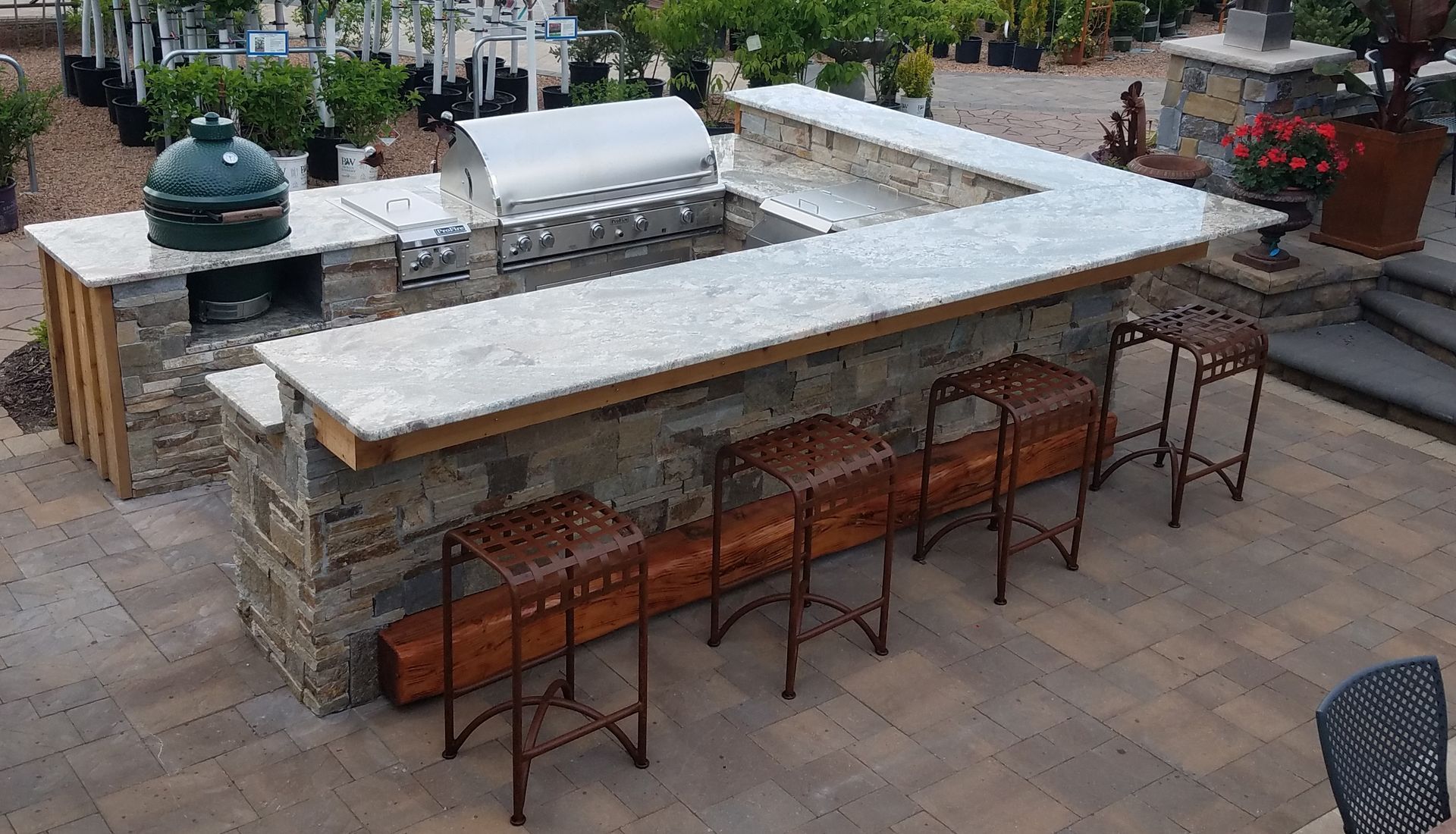 Outdoor stone kitchen with grill, Big Green Egg, countertop, and bar stools.
