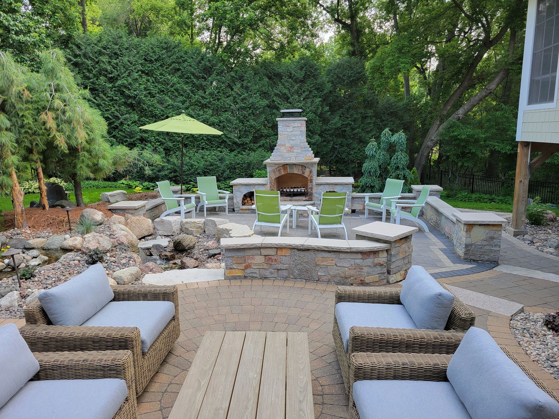 Outdoor patio with fireplace, seating areas, and greenery.