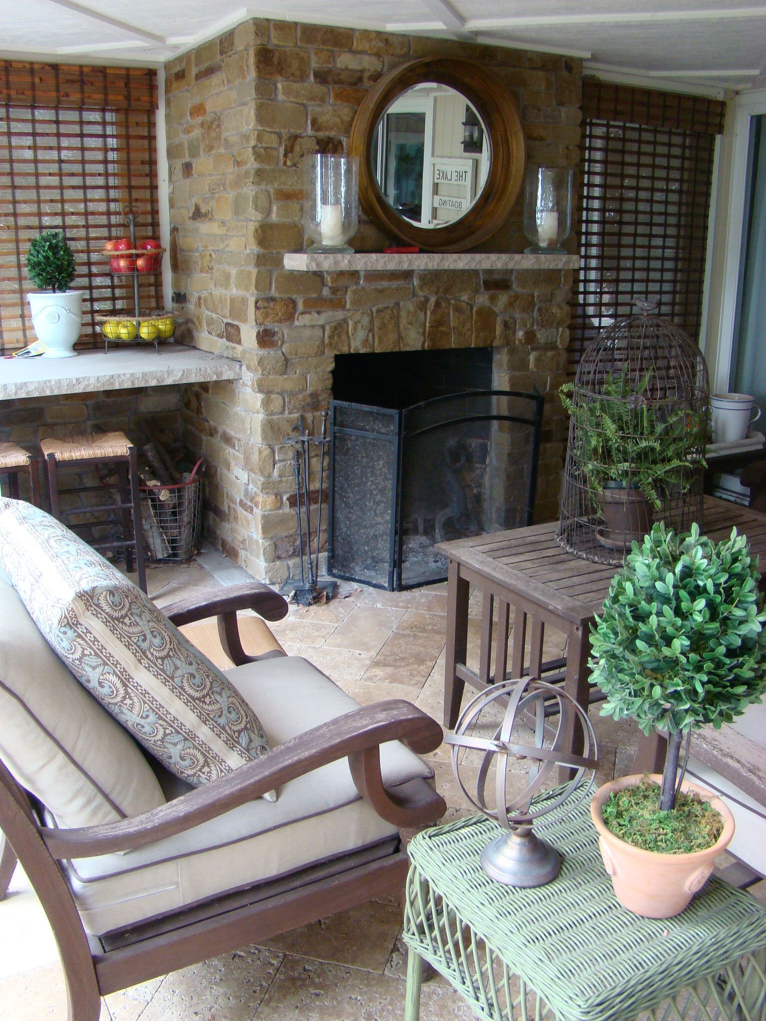 Outdoor seating area with brick fireplace, mirror, and two lounge chairs.
