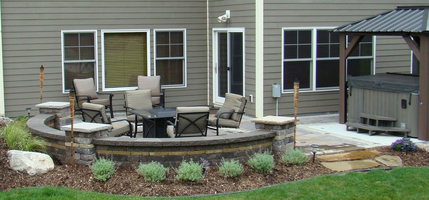 Backyard patio with fire pit, seating, and hot tub under a pergola.