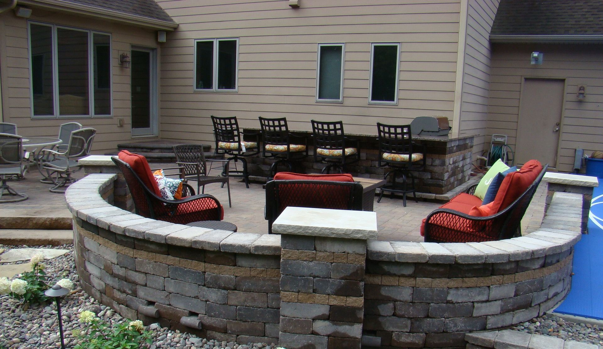 Outdoor patio with seating, brick retaining wall, and built-in bar area.