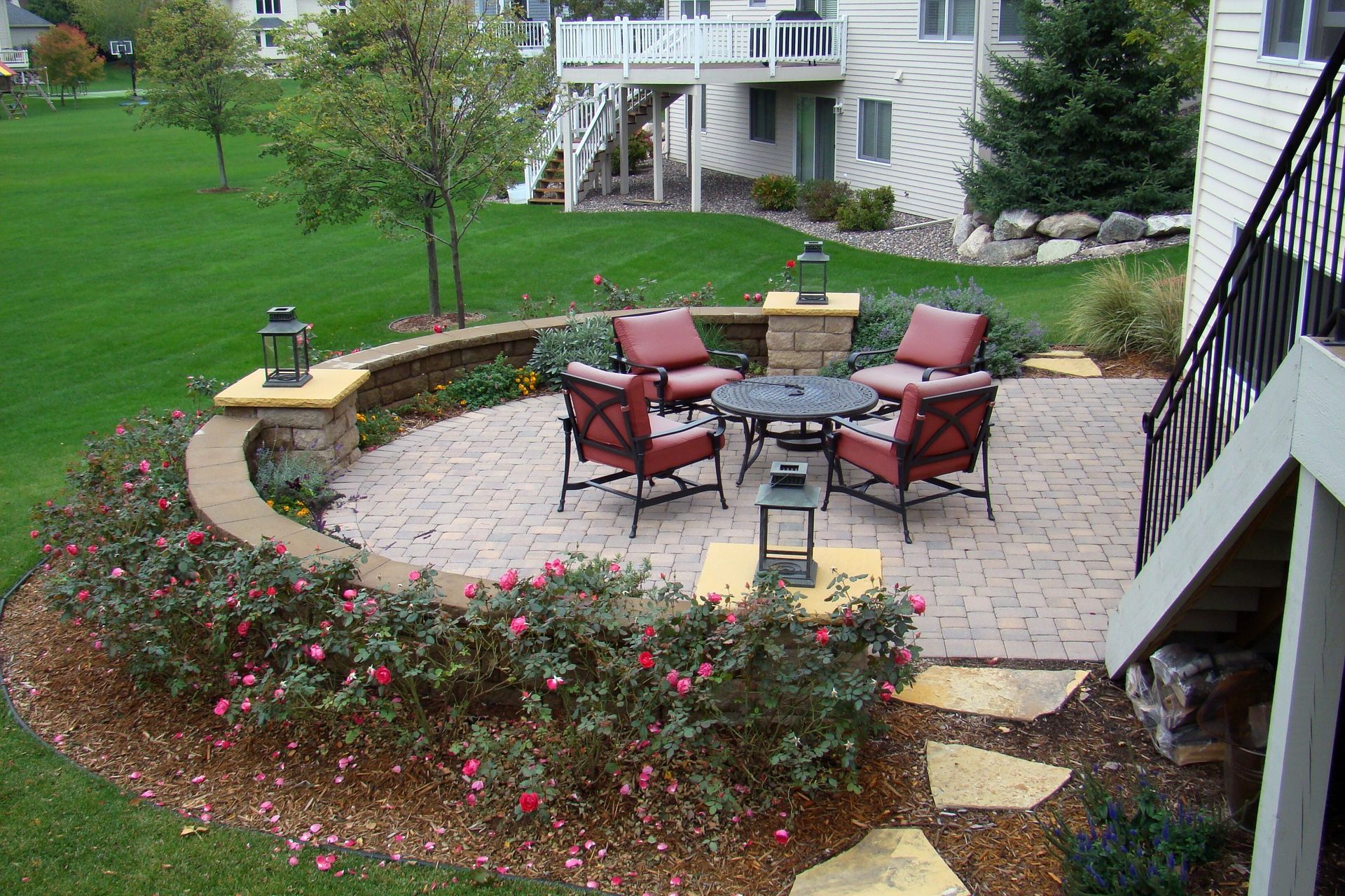Brick patio with outdoor seating, surrounded by landscaping and lawn.