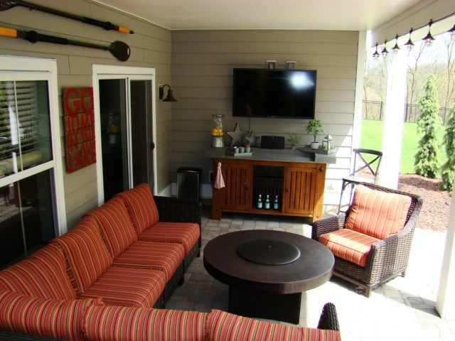 Covered patio with orange seating, a TV, and a fire pit.