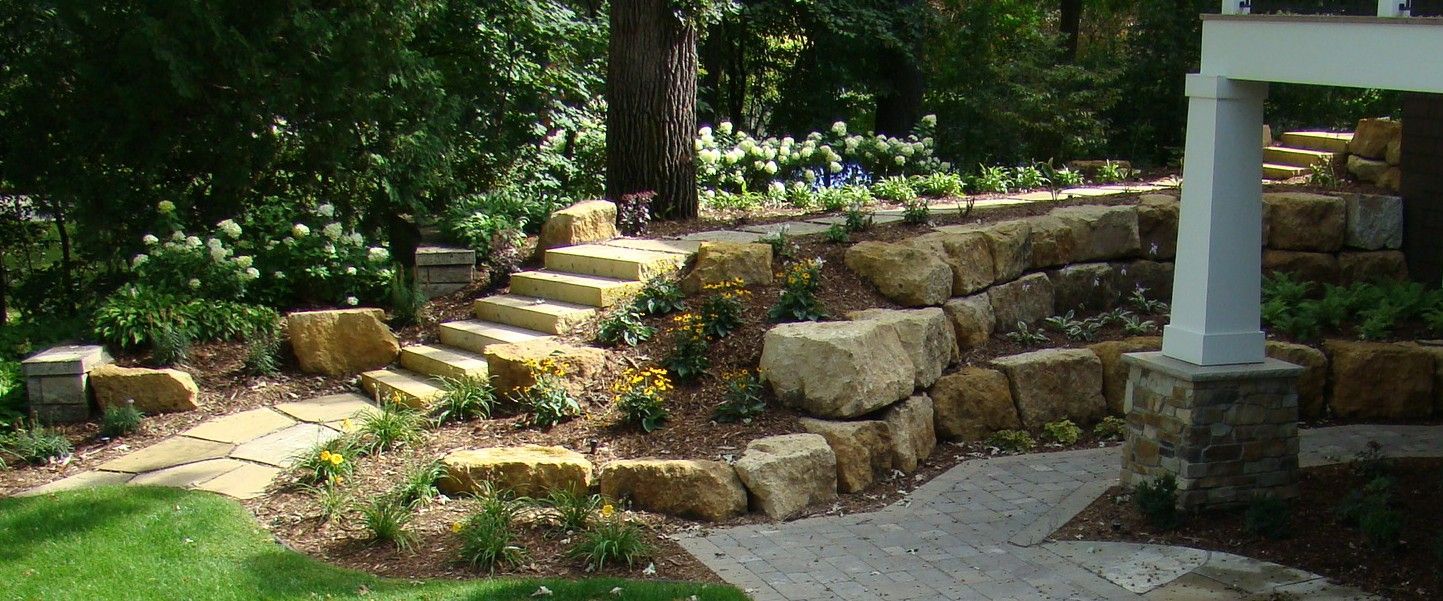 Stone steps and retaining wall in a landscaped yard.