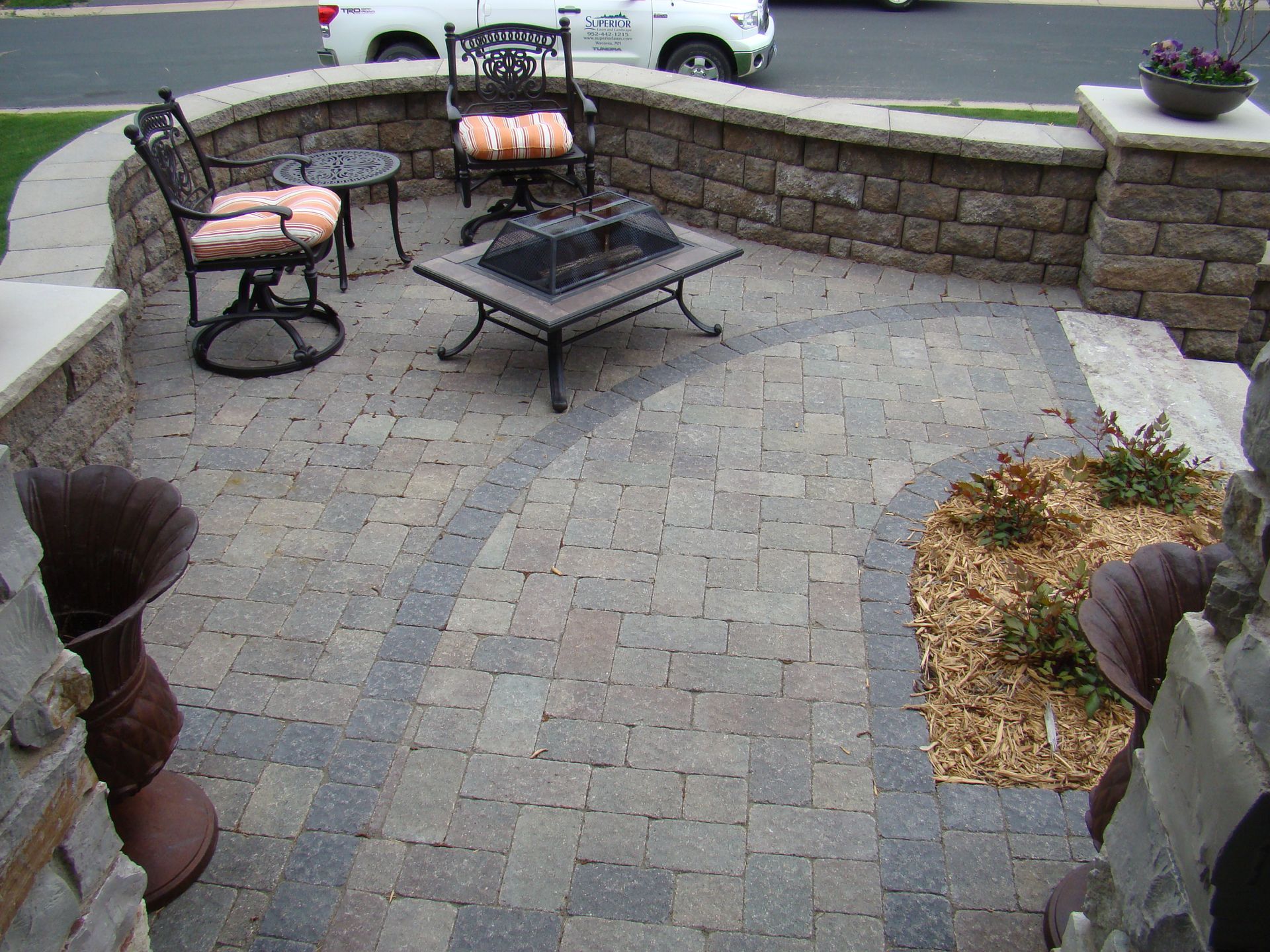 Brick patio with seating area, fire pit, and decorative stone walls.