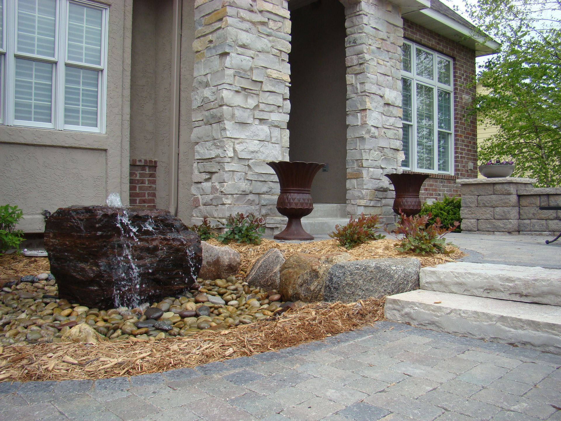 Stone facade entrance with water fountain and urns.