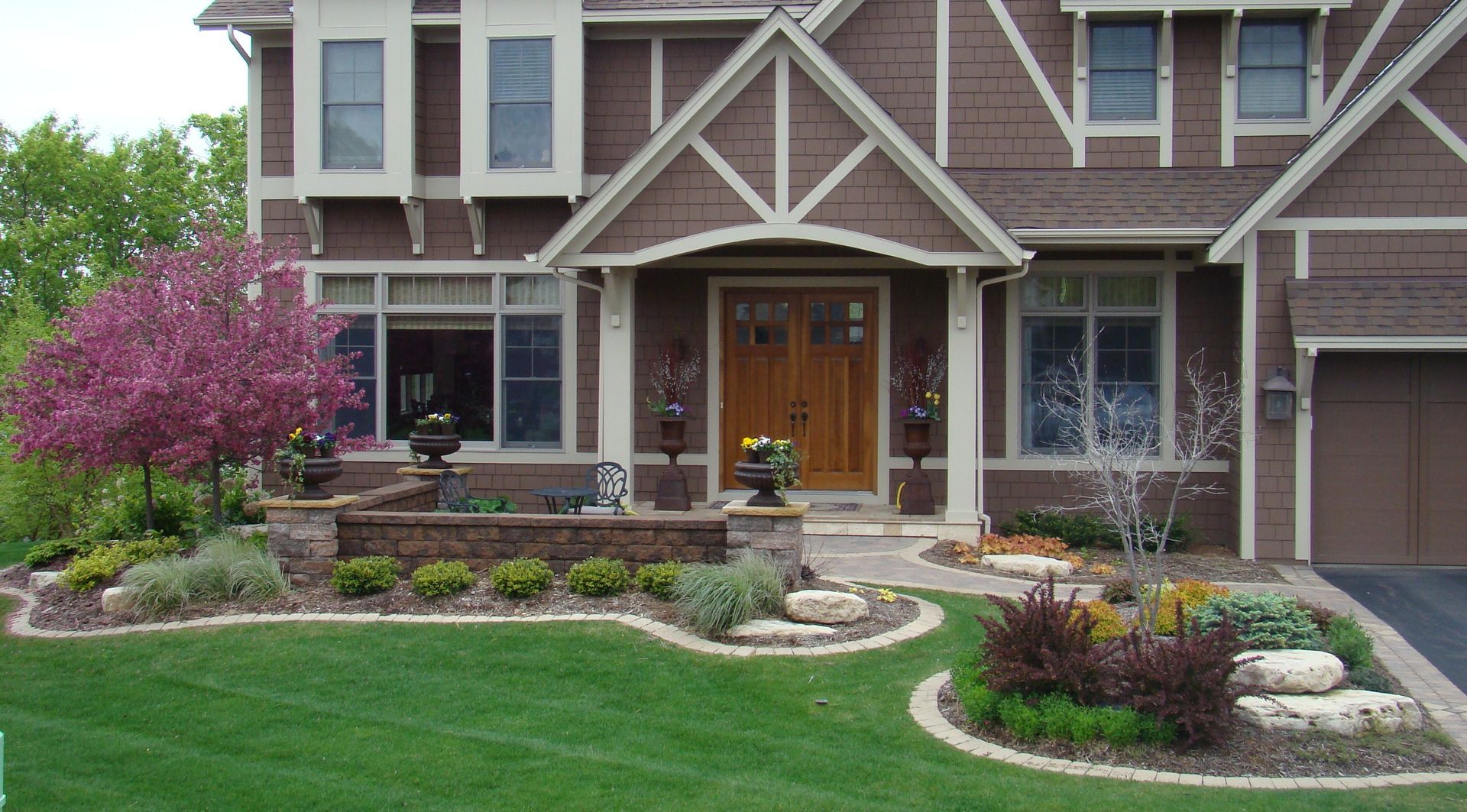 Brown house with manicured landscaping and a flowering tree.
