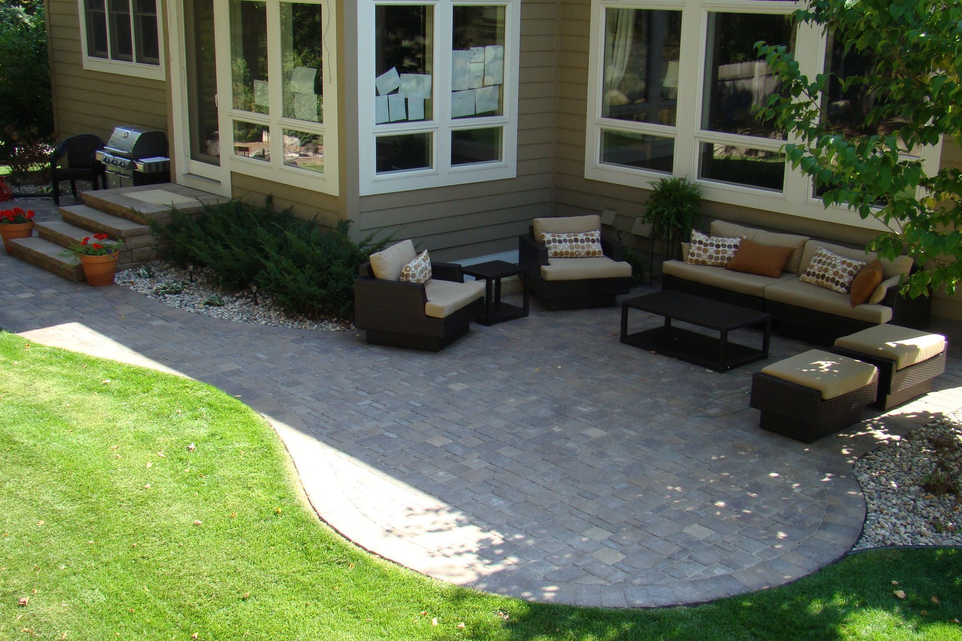 Patio with outdoor furniture, adjacent to a house, green grass, sunny day.