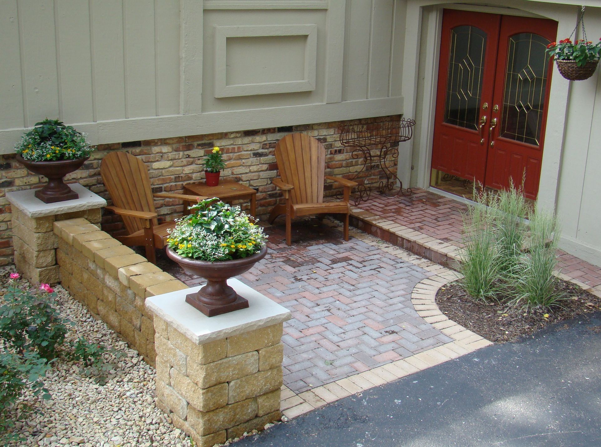 Brick patio with seating area, red double doors, and decorative planters.