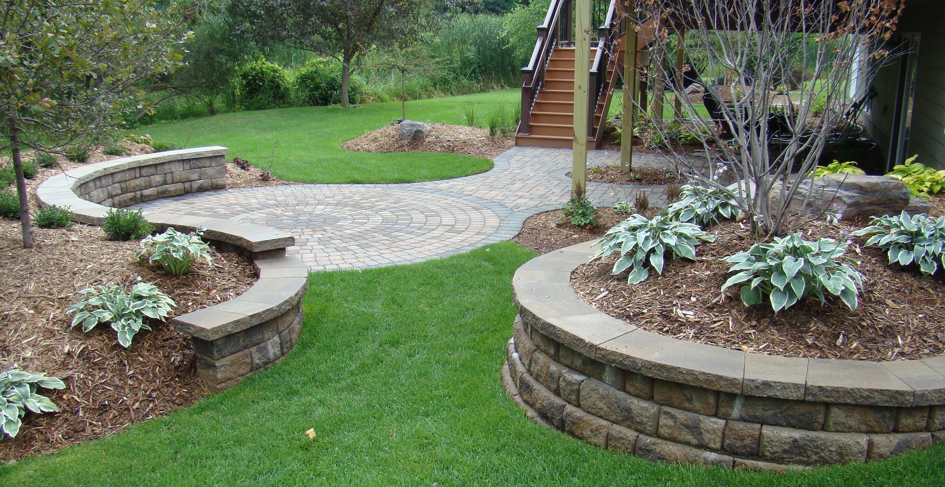 Landscaped backyard with stone pathways, retaining walls, and planted areas.