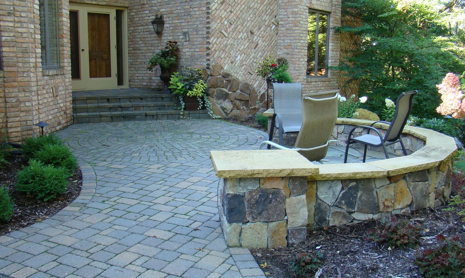 Brick home exterior with stone patio, fire pit, and seating.