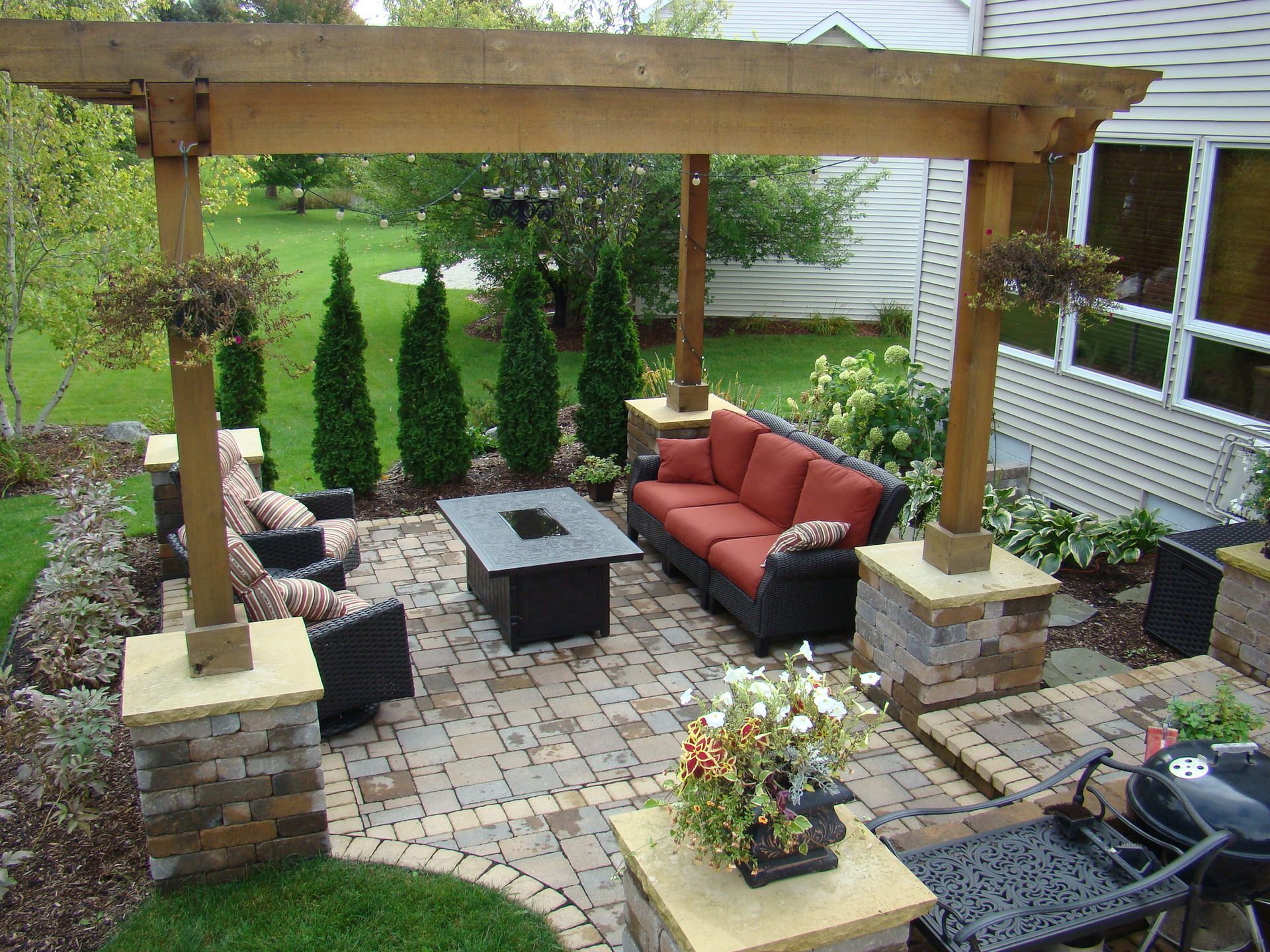 Patio with pergola, seating area, fire pit, brick pavers, and landscaping.