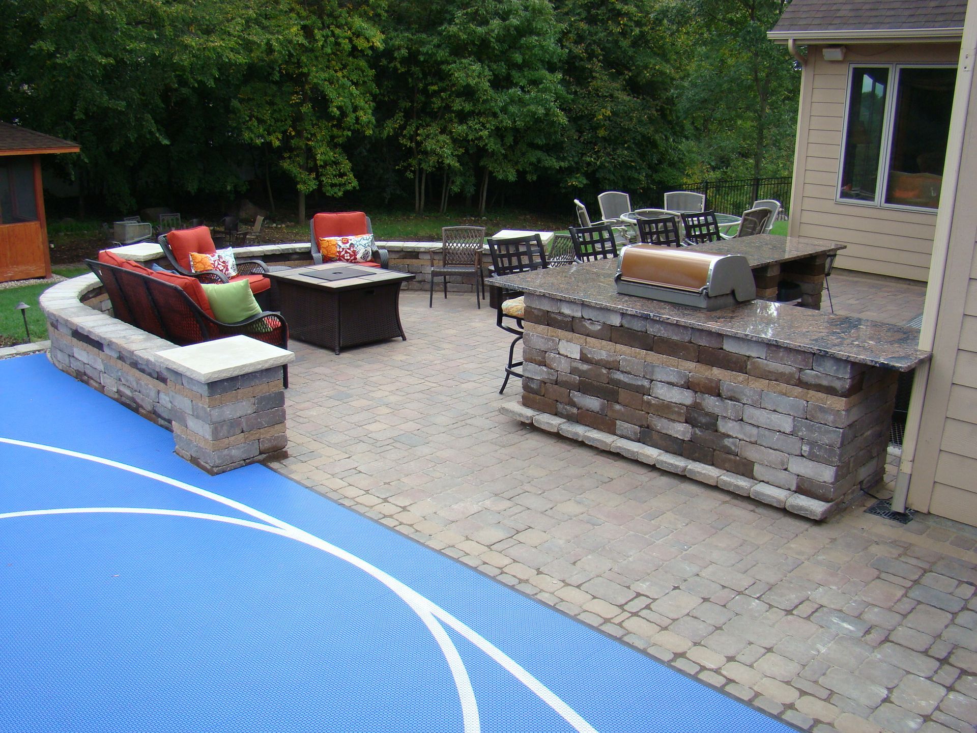 Patio with outdoor kitchen, seating area, and blue pool cover.