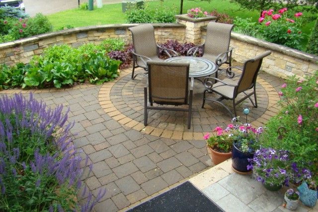 Patio with brick pavers, seating area, and surrounding flower beds.