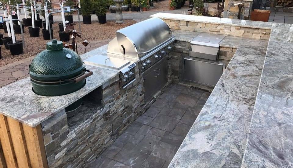 Outdoor kitchen with granite countertops, stainless steel grill, and Big Green Egg.