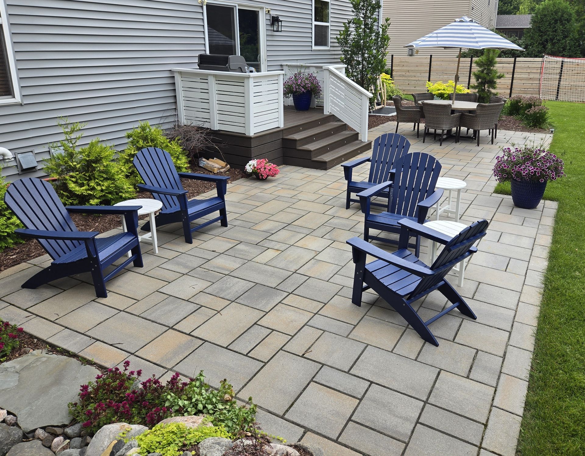 Patio with blue Adirondack chairs, a dining set, and a built-in outdoor kitchen.