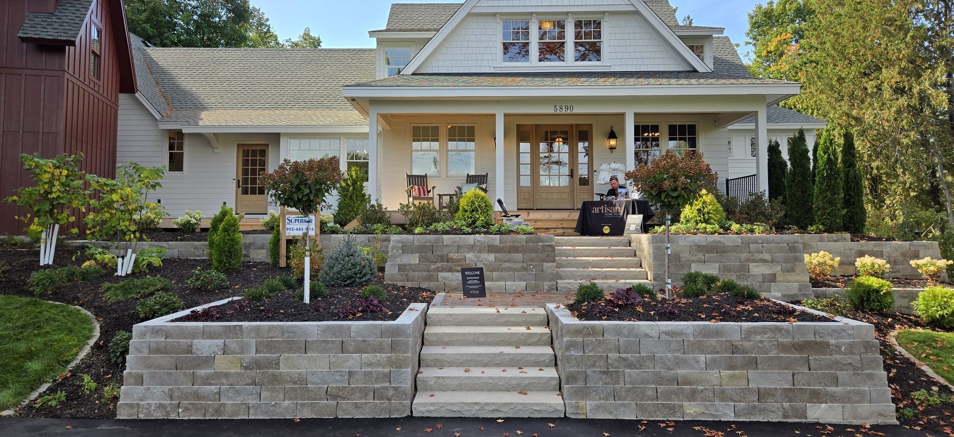 White house with a porch and tiered stone landscaping leading to the entrance.