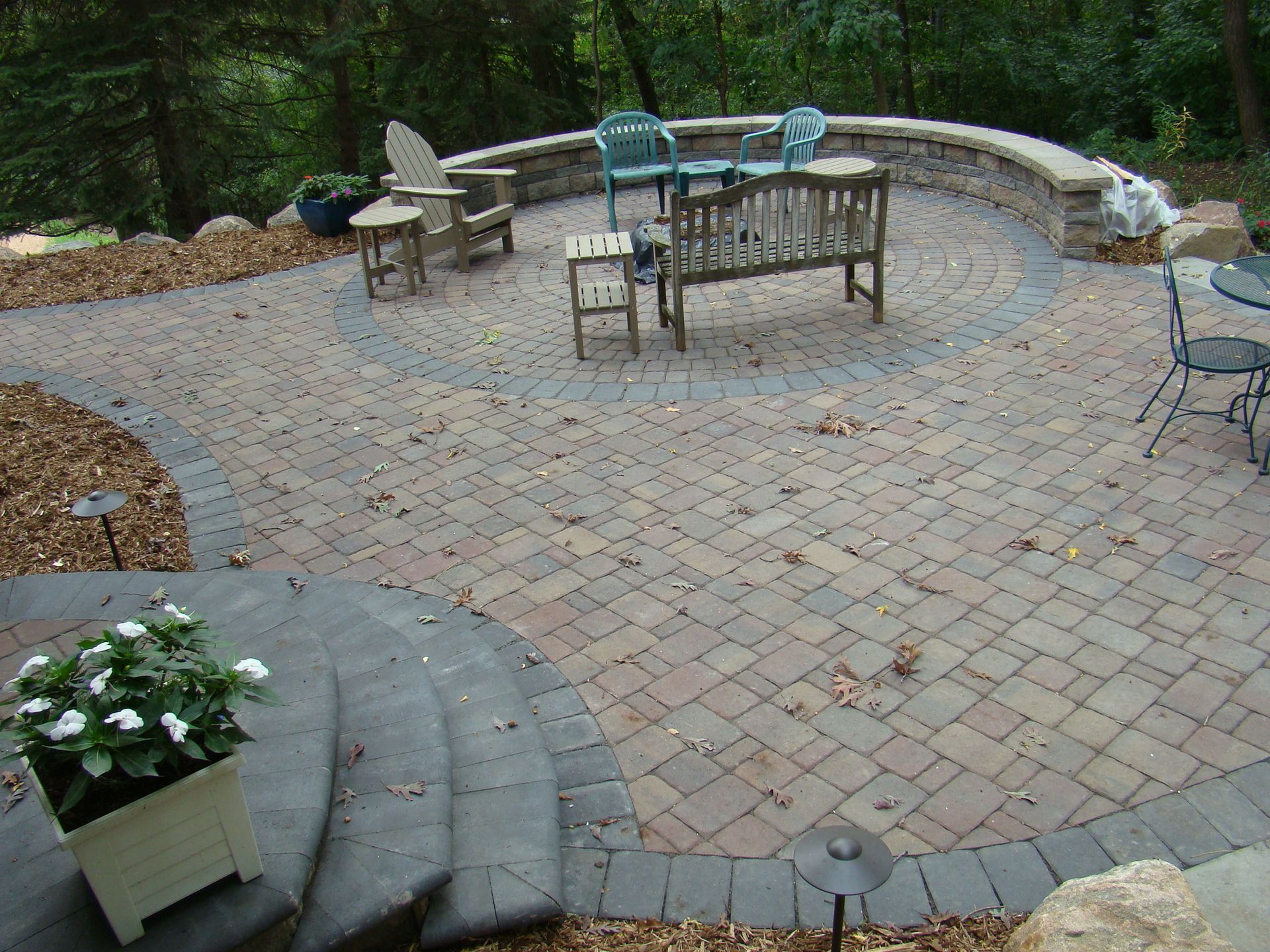 Stone patio with seating areas, steps, and surrounding landscaping.