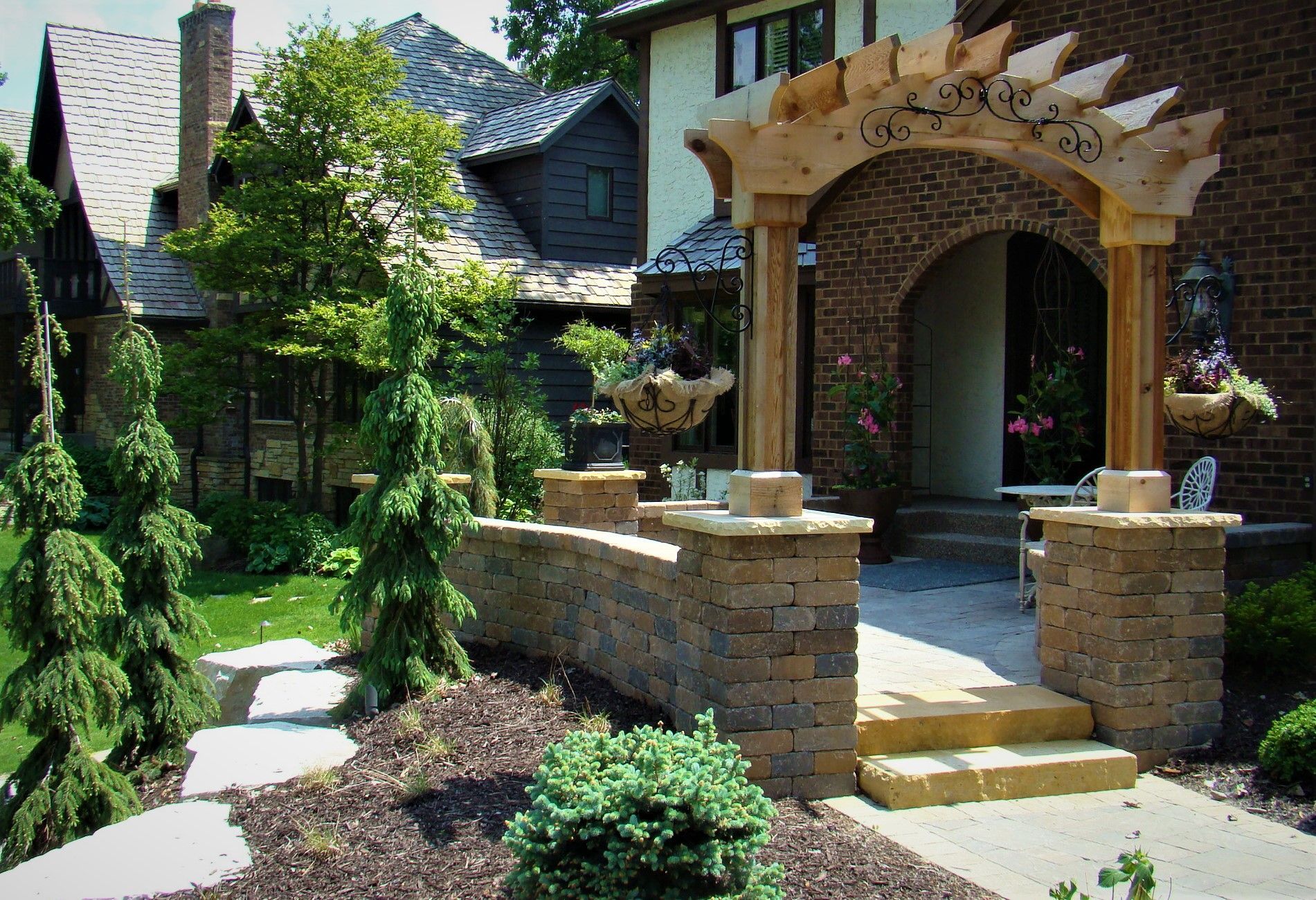 Stone archway entrance with columns, leading to a brick home.