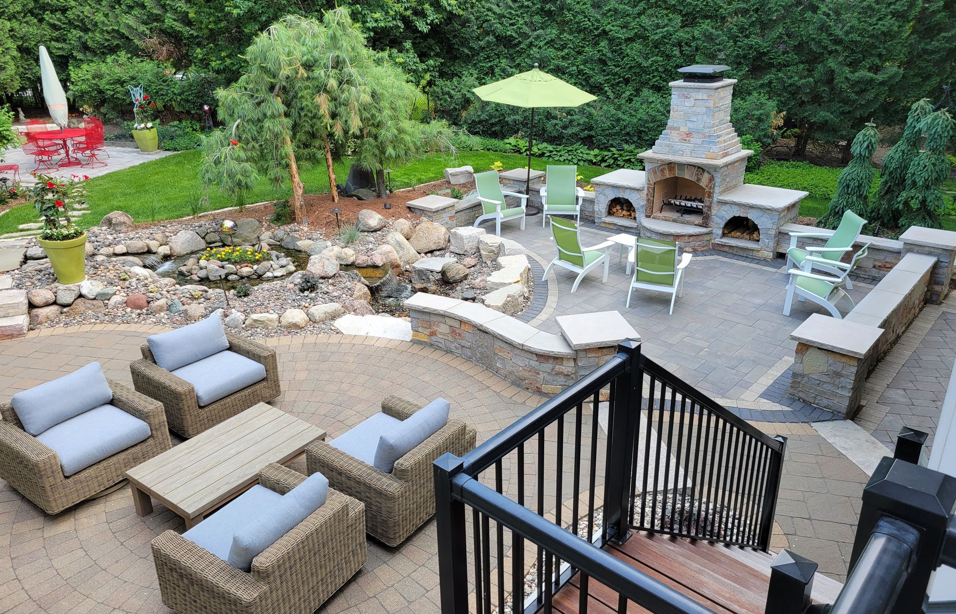 Outdoor patio with seating, fireplace, pond, and umbrella.