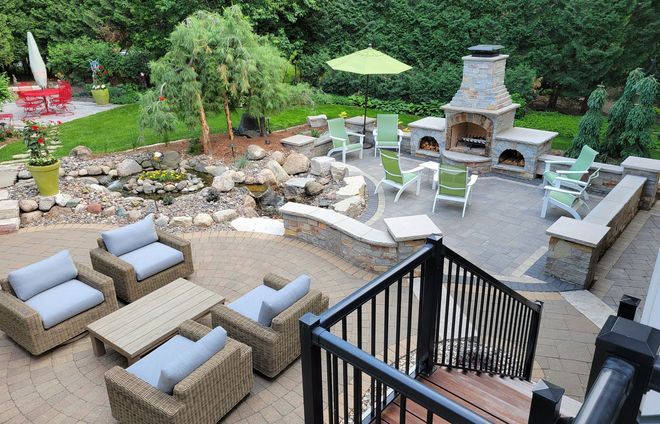 Outdoor patio with seating, fireplace, pond, and umbrella.