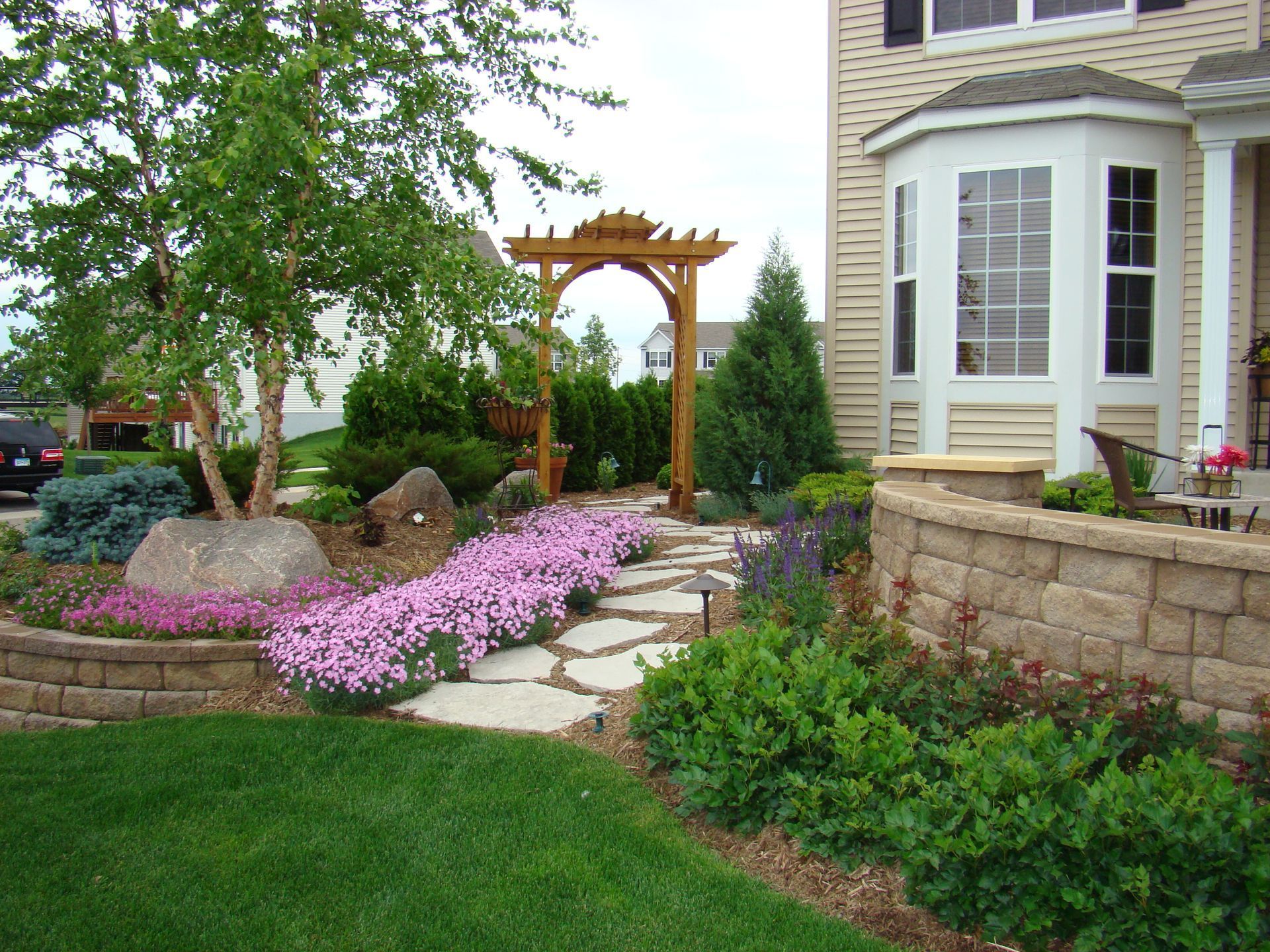 Brick patio with outdoor seating, surrounded by landscaping and lawn.