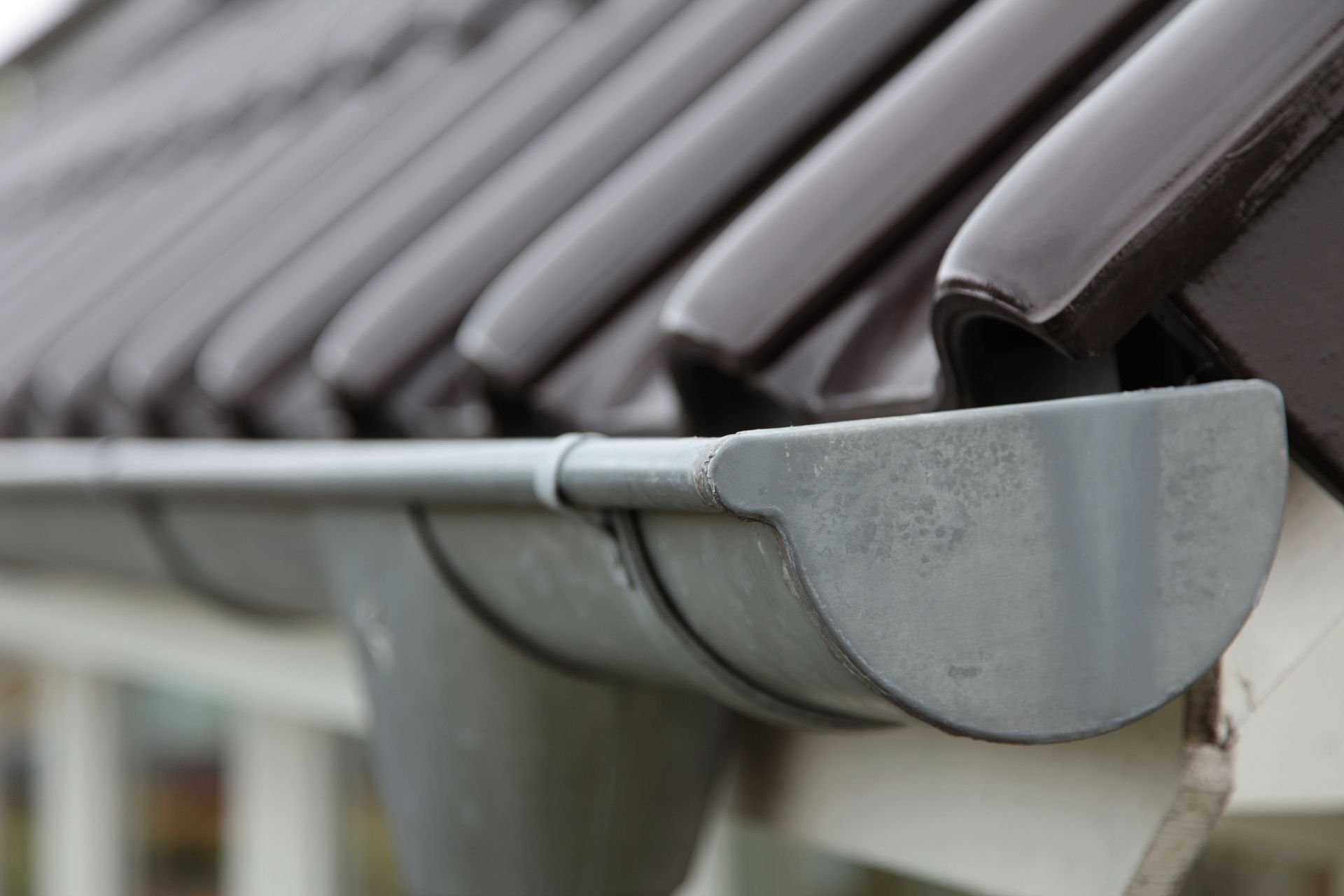Gray gutter beneath brown roof tiles.