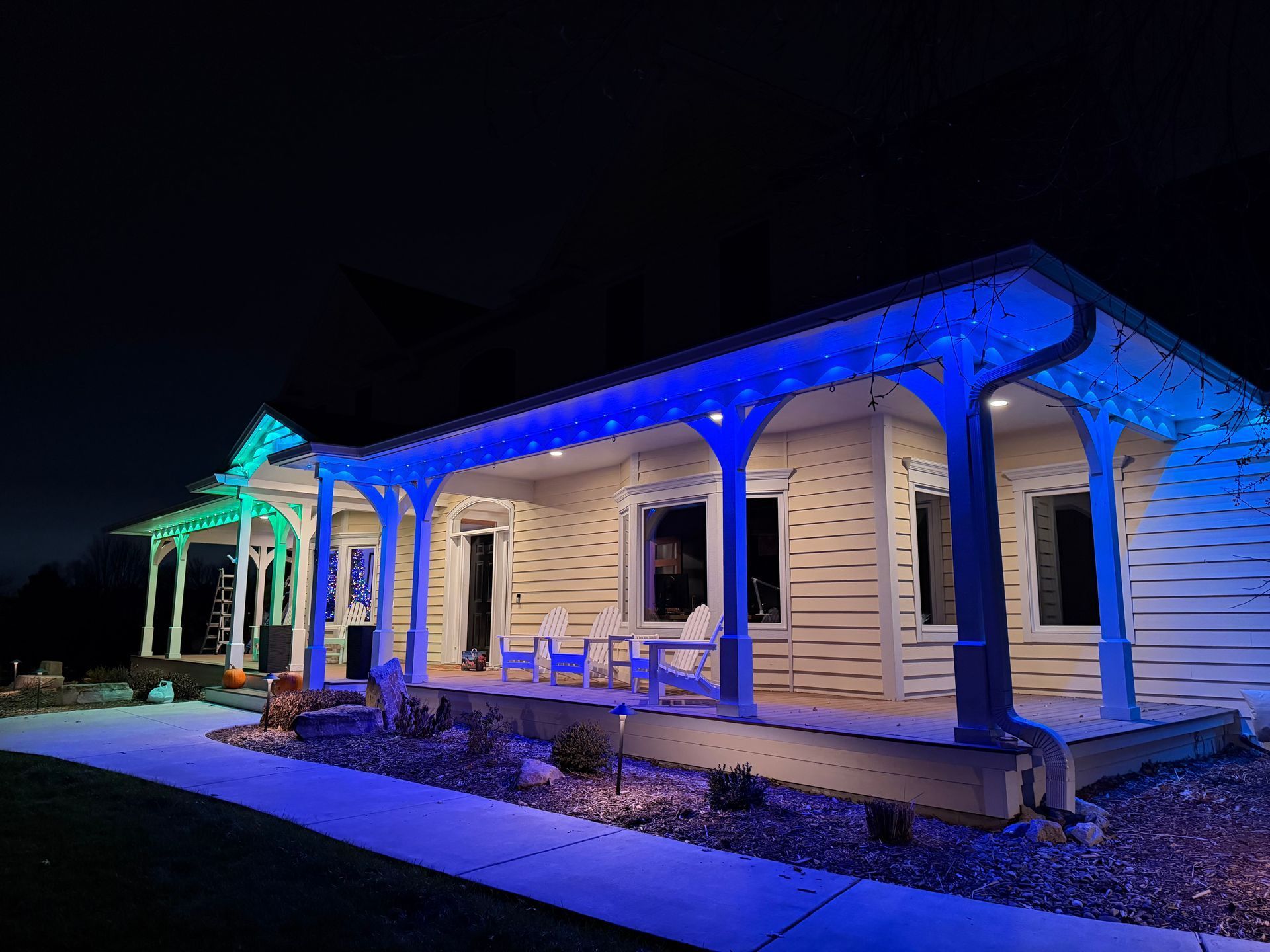 House with porch lit by blue and green lights at night.
