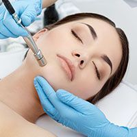 A woman is getting a facial treatment with a machine.