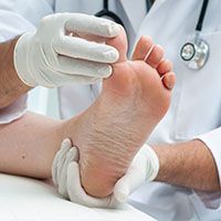 A doctor is examining a patient 's foot with a stethoscope.