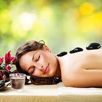 A woman is laying on a table with hot rocks on her back.