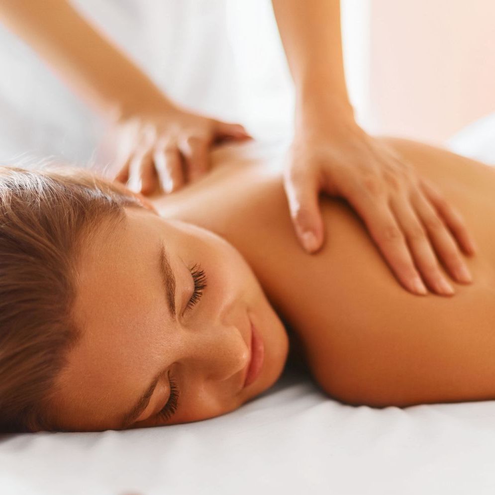 A woman is laying on a bed getting a massage.