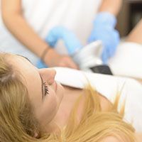 A woman is laying on a bed getting a facial treatment.