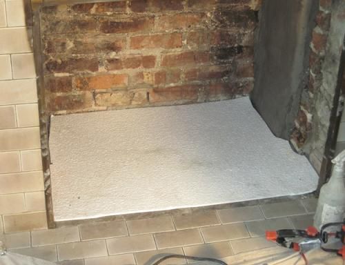 Fireplace interior with a white hearth and exposed brick.