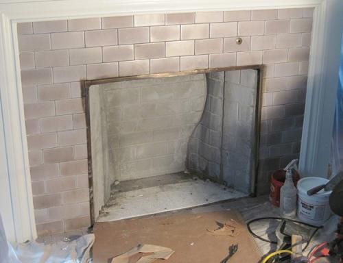 Fireplace with brick surround, unfinished interior, light pinkish bricks, room under construction.