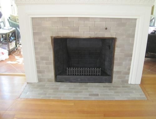 Fireplace with gray brick and white mantel in a room with hardwood floors.