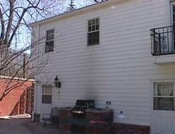 White building with windows, a small balcony, and a brick patio.