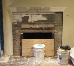 Fireplace under construction, wood and stone with a wooden panel covering the opening, with two paint buckets.